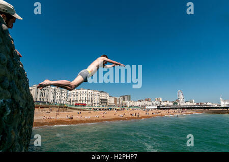 Gli adolescenti che salta da pennelli sulla spiaggia di Brighton nel mare in un pomeriggio caldo. Foto Stock