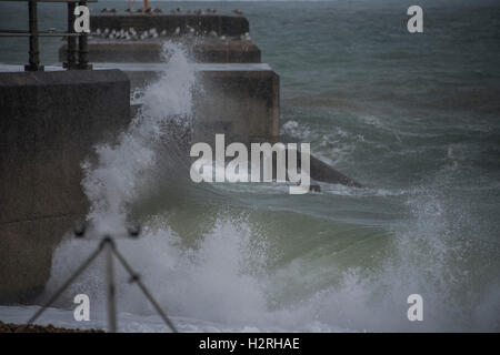 Hastings, Sussex, Regno Unito. 1 Ottobre, 2016. Onde infrangersi sulla spiaggia di difese - Le persone godono di una miscela di sole e di docce in una giornata di vento sulla spiaggia di Hatings. 01 ott 2016 Credit: Guy Bell/Alamy Live News Foto Stock