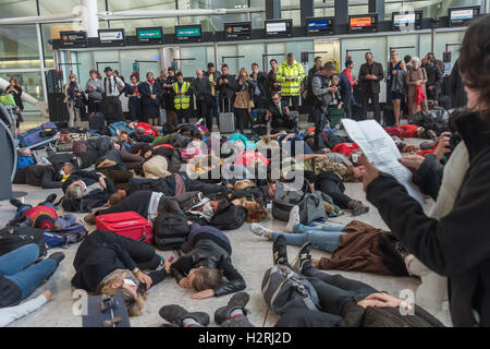 Aeroporto di Heathrow di Londra, Regno Unito. 1 ottobre 2016. Come parte di un'ondata globale di resistenza all'aeroporto espansione su ambiente e motivi sociali, diverse centinaia di manifestanti stadio un flash mob protesta all'interno del Terminal 2 di Heathrow, inizio con una matrice, con 'frequenti volantini a scavalcare i loro corpi morti e bagagli per un champagne fast track check-in desk, seguito da canti e balli. #StayGrounded protesta fu organizzata da rivendicare il potere, che ha anche messo in scena una 'red' linea di protesta da parte di ciclisti in aeroporto allo stesso tempo. Peter Marshall / Alamy Live News Foto Stock