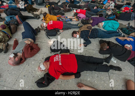 Aeroporto di Heathrow di Londra, Regno Unito. 1 ottobre 2016. Come parte di un'ondata globale di resistenza all'aeroporto espansione su ambiente e motivi sociali, diverse centinaia di manifestanti stadio un flash mob protesta all'interno del Terminal 2 di Heathrow, inizio con una matrice, con 'frequenti volantini a scavalcare i loro corpi morti e bagagli per un champagne fast track check-in desk, seguito da canti e balli. #StayGrounded protesta fu organizzata da rivendicare il potere, che ha anche messo in scena una 'red' linea di protesta da parte di ciclisti in aeroporto allo stesso tempo. Peter Marshall / Alamy Live News Foto Stock