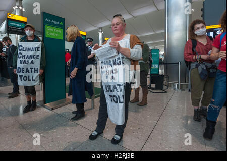 Aeroporto di Heathrow di Londra, Regno Unito. 1 ottobre 2016. Come parte di un'ondata globale di resistenza all'aeroporto espansione su ambiente e motivi sociali, diverse centinaia di manifestanti stadio un flash mob protesta all'interno del Terminal 2 di Heathrow, inizio con una matrice, con 'frequenti volantini a scavalcare i loro corpi morti e bagagli per un champagne fast track check-in desk, seguito da canti e balli. Manifestanti stand con "il cambiamento climatico è una morte pedaggio" banner a Aer Lingus GOld Circle Check-in. #StayGrounded protesta fu organizzata da rivendicare il potere, che ha anche messo in scena una 'red' linea di protesta da parte di ciclisti a Foto Stock