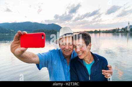 Uomo e donna sorridente, prendendo foto con il telefono cellulare, selfie, Schliersee, Alta Baviera, Baviera, Germania Foto Stock