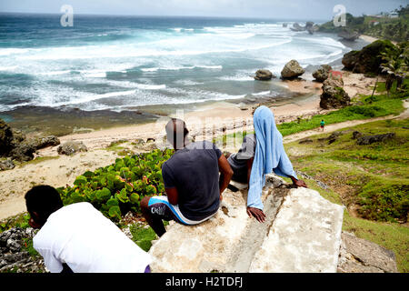 Barbados costa atlantica vista oceano uomini locali ragazzi sat che guarda al mare di riposo rilassante sat sul faggio in pietra vista in elevazione alta Foto Stock