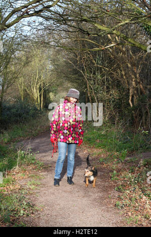 Donna cane a piedi lungo la strada di campagna in inverno Foto Stock