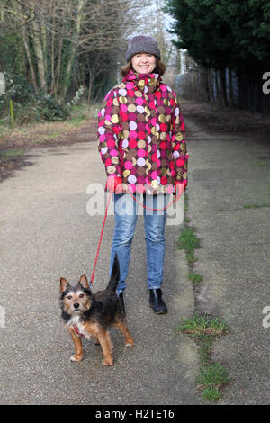 Donna cane a piedi lungo la strada di campagna in inverno Foto Stock