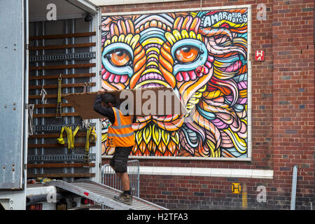 Pedoni che passano dall'arte di strada, dai graffiti alla pittura della parete, alla decorazione, al sole, allo Spray e all'arte Festival Art in East Topping Street, Blackpool, Lancashire, Regno Unito Foto Stock