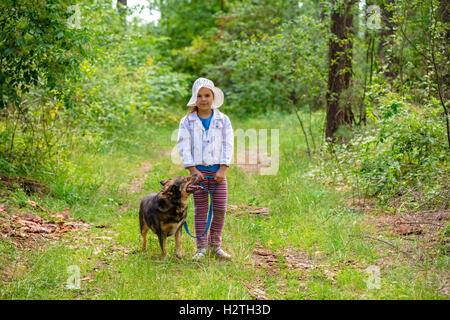 Felice bambina giocando con il cane nella foresta Foto Stock