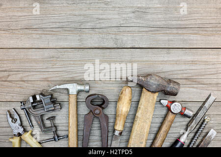 In legno listone grigio sfondo tabella con varie vecchie e arrugginite strumenti e utensili a mano su di esso Foto Stock