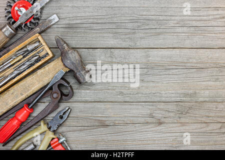 Set di vari vecchi utensili a mano comprendente un martello e pinze pinza su grigio di tavole di legno sfondo Foto Stock