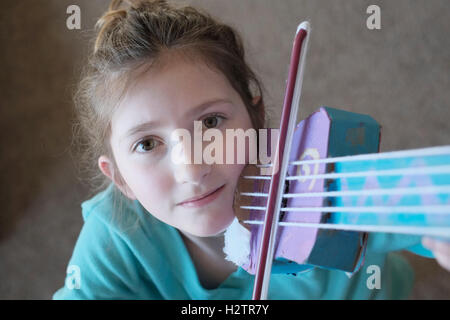 Ritratto di giovane ragazza che gioca un giocattolo di violino per divertimento carino e bella Foto Stock