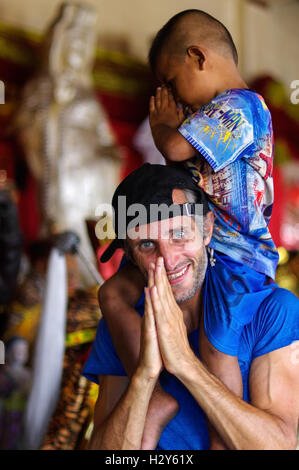 Un ragazzo grazioso godendo di cavalcare sull'uomo torna, Phuket Foto Stock