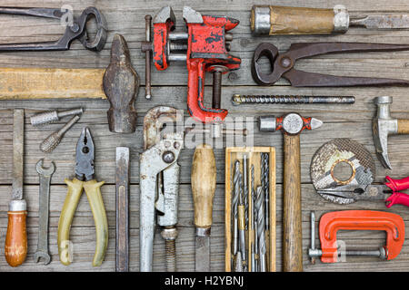 Il vecchio gli strumenti a mano impostare compresi pinze, martelli, cacciavite, chiavi e pinze su grigio di tavole di legno sfondo, design piatto Foto Stock