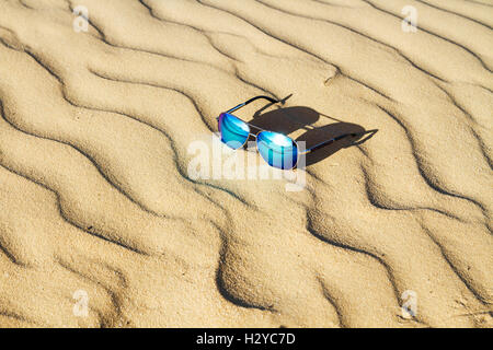 Occhiali da sole sulla sabbia , estate deserto è riflessa nei bicchieri. Foto Stock