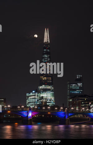 Luna piena sopra il notturno illuminato il grattacielo Shard e dello skyline di Southwark dietro il fiume Tamigi, London, Regno Unito Foto Stock