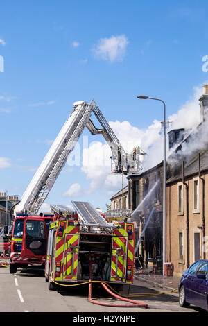 Scottish fuoco e il servizio di soccorso dei Vigili del fuoco su una scala di affrontare un edificio in fiamme in Elie e Earlsferry, Fife, Scozia, Regno Unito Foto Stock