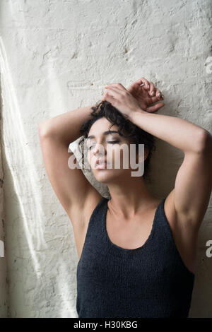 Bella donna in piedi contro il muro le mani sopra la testa Foto Stock