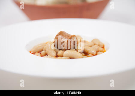 Vista dettagliata del bianco piastra circolare con spezzatino con fagioli e salsiccia rossa, cibo tipico spagnolo native da Asturias Spagna betwee Foto Stock