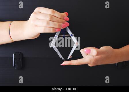 Mani tenendo una bussola tecnico su un vecchio e rovinato valigetta nera Foto Stock