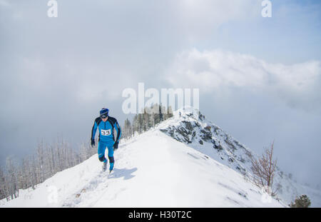 Arshan, Russia - 04.2015: giovane laghetto in esecuzione con bastoni da passeggio in mani durante una neve шт maratona di montagna. Foto Stock