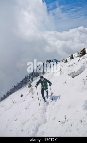 Arshan, Russia - 04.2015: giovane laghetto in esecuzione con bastoni da passeggio in mani durante una neve шт maratona di montagna. Foto Stock