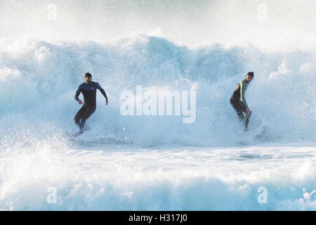 Lone surfer rides enorme back lit sunshine surf REGNO UNITO Foto Stock