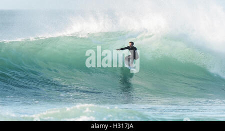 Lone surfer rides enorme back lit sunshine surf REGNO UNITO Foto Stock