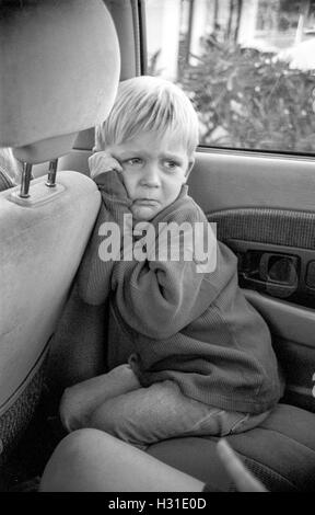 Un arrabbiato, busbana francese toddler boy acciglia nel sedile posteriore del suo genitore auto in Corona, CA. Modello di rilascio Foto Stock