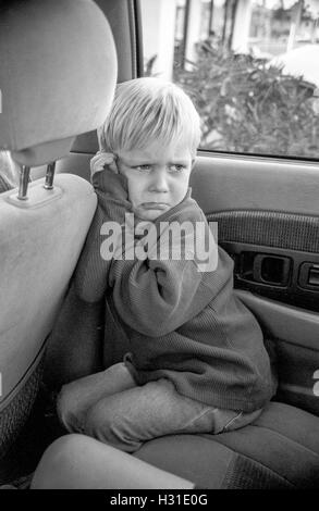 Un arrabbiato, busbana francese toddler boy acciglia nel sedile posteriore del suo genitore auto in Corona, CA. Modello di rilascio Foto Stock