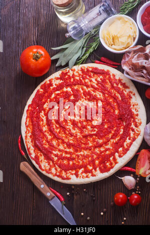 Pizza e gli ingredienti sul tavolo di legno Foto Stock