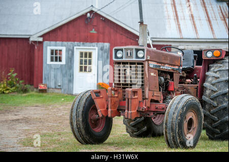 Il vecchio trattore rosso nella parte anteriore di un fienile su un frutteto di Livermore, Maine. Foto Stock