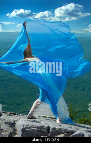 Ballerino femmina in abito bianco ballando con tessuto blu nel vento sulla cima di Mt. Kearsarge, New Hampshire. Foto Stock