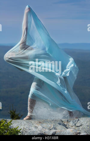 Ballerino femmina in abito bianco avvolto all'interno di tessuto verde al vento sulla cima di Mt. Kearsarge, New Hampshire. Foto Stock