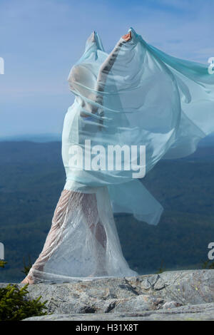 Ballerino femmina in abito bianco avvolto all'interno di tessuto verde al vento sulla cima di Mt. Kearsarge, New Hampshire. Foto Stock