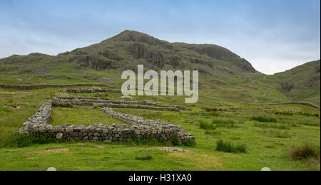 Ampie pareti in pietra, parte delle rovine dell antica fortificazione romana con ampia vista del brulla colline smeraldo a Hardknott Pass, Lake District, Cumbria Inghilterra England Foto Stock