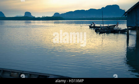 Phang-Nga, Thailandia - Agosto 9,2014: Thai pescatore in coda lunga barca da pesca a Samchong borgo peschereccio di sunrise in Phang-Ng Foto Stock