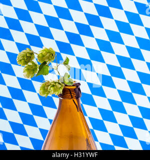 Bottiglia di birra con hop branch, su bianco blu bandiera bavarese Foto Stock