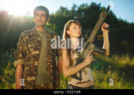 Bianco giovane ragazza e un uomo arabo in camuffamento con un'arma nelle mani di all'aperto Foto Stock