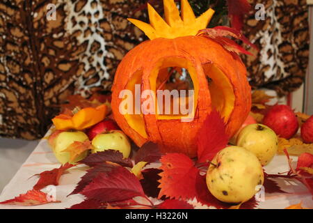 Arancio brillante zucca tagliata in forma di carrello Cenerentola decorata di foglie e di mele per la festa di Halloween Foto Stock