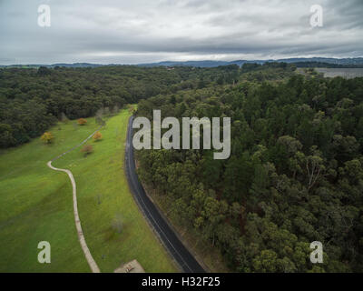 Vista aerea del serbatoio Cardinia Park - area erbosa, percorso a piedi, strada tortuosa e foresta. Melbourne, Victoria, Australia Foto Stock