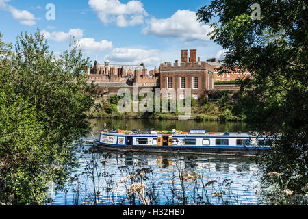 Una narrowboat che passa dall'Hampton Court Palace sul Fiume Tamigi a Surrey, Inghilterra, Regno Unito Foto Stock