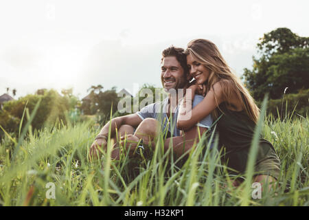 Colpo all'aperto di giovani felici gli amanti seduti sul prato. Felice coppia giovane in erba. Foto Stock