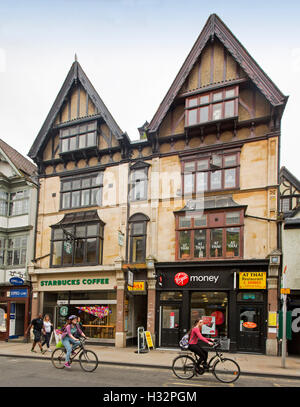 Starbucks ristorante in un edificio storico nella città inglese di Oxford con pedoni e persone in bicicletta passando da Foto Stock