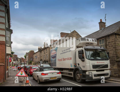 Lavori in strada stretta nel villaggio inglese di Belper con semaforo, segni e la congestione del traffico con vetture e autocarri Foto Stock