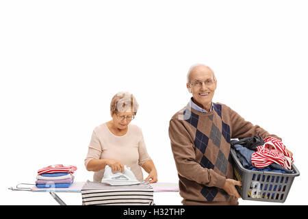 Allegro uomo anziano tenendo un cesto per la biancheria e una donna matura a stirare isolati su sfondo bianco Foto Stock