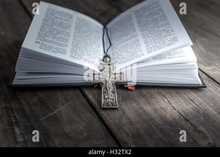 Primo piano della croce cristiana collana giacente su una pagina aperta della bibbia. Foto Stock