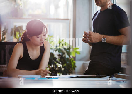 Colpo di due giovani business partner per discutere di nuove idee in ufficio. I giovani a lavorare insieme su un nuovo progetto di business. Foto Stock