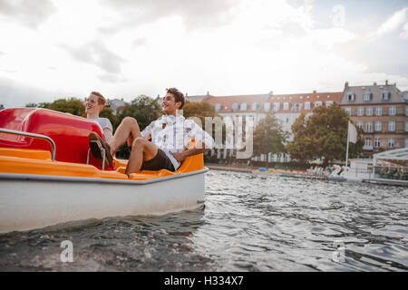 All'aperto colpo di due giovani amici seduti in barca a pedali. Ragazzi adolescenti godendo di gite in barca nel lago. Foto Stock