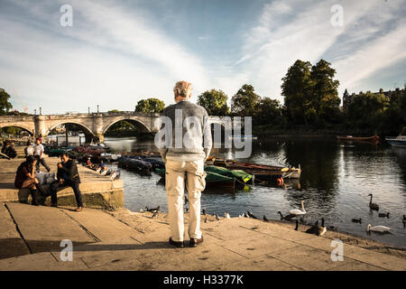 Un uomo anziano isolato che guarda il Ponte di Richmond e il Tamigi a Richmond upon Thames, Londra, Regno Unito Foto Stock