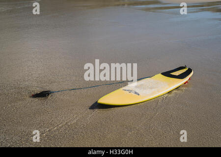 Una solitaria la tavola da surf a sinistra sulla spiaggia di Sennen Cove, Cornwall Foto Stock