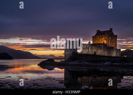 Illuminata Eilean Donan Castle al tramonto in Loch Duich, Ross and Cromarty, Highlands occidentali della Scozia, Regno Unito Foto Stock